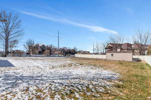 Snowy yard with a residential view and fence