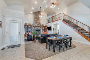 Dining room featuring tile patterned flooring, stairs, arched walkways, high vaulted ceiling, and a ceiling fan