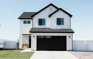 Modern inspired farmhouse with board and batten siding, an attached garage, and a gate with an RV pad going down the side of the home.
