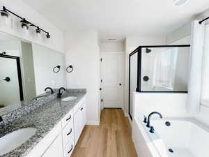 Master Bathroom with a stall shower, deep soaking bath tub, two sinks, and wood finished floors