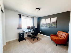 Office space/Bedroom 1 with a light carpet and accent wall