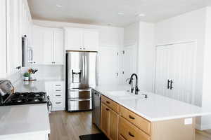 Kitchen with light wood-style flooring, stainless steel appliances, light countertops, and a sink