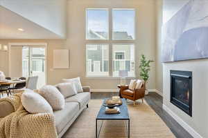 Living room with dark wood finished floors, a glass covered fireplace, and a wealth of natural light