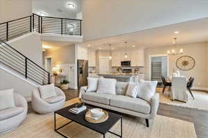 Living area with visible vents, light wood-style flooring, recessed lighting, an inviting chandelier, and a towering ceiling