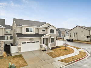 Townhome / multi-family property featuring an attached garage, fence, board and batten siding, and stone siding