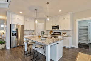 Kitchen with white cabinetry, dark wood-type flooring, a breakfast bar area, and stainless steel appliances
