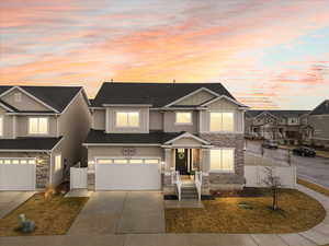 View of front of property featuring board and batten siding, a garage, fence, and stone siding