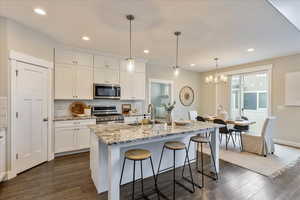 Kitchen with a sink, a kitchen breakfast bar, stainless steel appliances, white cabinets, and decorative backsplash