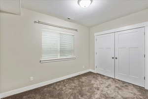 Unfurnished bedroom featuring visible vents, baseboards, carpet, a closet, and a textured ceiling