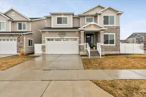 Craftsman house with fence, driveway, a garage, stone siding, and board and batten siding