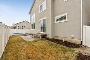 Back of property with a yard, a patio, a fenced backyard, and stucco siding