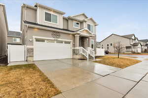 View of front of house with stone siding, fence, board and batten siding, concrete driveway, and an attached garage