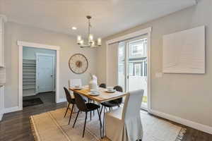 Dining space with baseboards, an inviting chandelier, and wood finished floors