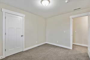 Empty room with visible vents, baseboards, carpet, and a textured ceiling
