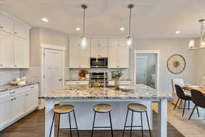 Kitchen featuring white cabinetry, a kitchen breakfast bar, dark wood finished floors, and stainless steel appliances