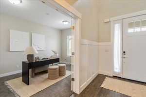 Entryway with visible vents, baseboards, dark wood-style floors, and wainscoting