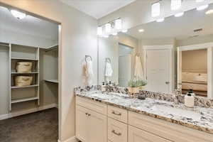 Bathroom featuring a sink, a closet, ensuite bath, and double vanity