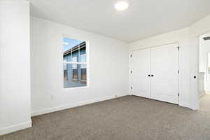 Unfurnished bedroom featuring a closet, baseboards, and carpet