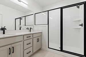 Bathroom with double vanity, a stall shower, and a sink
