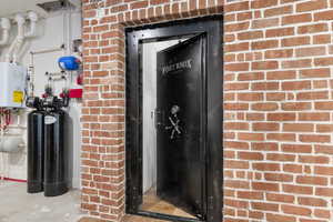 View of exterior entry with brick siding and tankless water heater