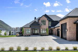 View of front of house with brick siding, roof with shingles, and a chimney