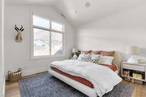 Bedroom featuring visible vents, baseboards, vaulted ceiling, and light wood finished floors