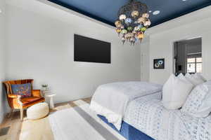 Bedroom with a notable chandelier, wood finished floors, visible vents, and baseboards