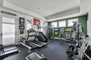 Workout area with a tray ceiling and baseboards
