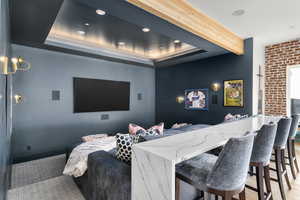 Home theater featuring a tray ceiling, beamed ceiling, baseboards, and carpet flooring