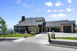 View of front of house with brick siding, roof with shingles, a garage, and concrete driveway