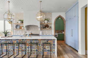 Kitchen featuring open shelves, tasteful backsplash, wood finished floors, wooden ceiling, and a chandelier