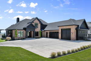 View of front facade featuring brick siding, driveway, a garage, a shingled roof, and a chimney