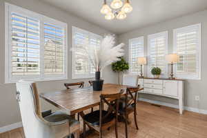 Dining space with light wood-type flooring, baseboards, a notable chandelier, and a healthy amount of sunlight