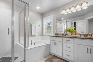 Full bathroom with double vanity, a stall shower, a sink, tile patterned floors, and a bath