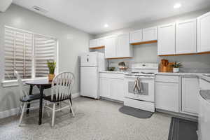 Kitchen featuring visible vents, baseboards, light countertops, recessed lighting, and white appliances