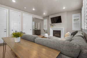 Living area with a glass covered fireplace, recessed lighting, and wood finished floors