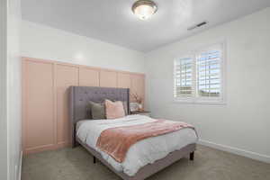 Bedroom featuring visible vents, light carpet, a textured ceiling, and baseboards