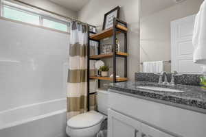 Bathroom featuring visible vents, toilet, vanity, and shower / tub combo