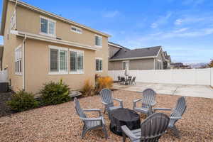 Back of house featuring a fenced backyard, stucco siding, an outdoor fire pit, and a patio