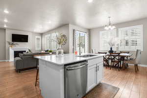 Kitchen featuring dishwasher, light wood-type flooring, an inviting chandelier, and a sink