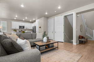 Living room with stairway, baseboards, light wood finished floors, recessed lighting, and a textured ceiling