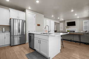 Kitchen with a sink, light wood-style floors, appliances with stainless steel finishes, and open floor plan