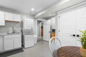 Laundry room featuring a sink, baseboards, stacked washer and dryer, and recessed lighting
