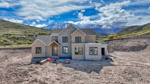 Property in mid-construction featuring roof with shingles, a mountain view, and stone siding