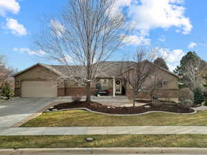 Rambler style home with beautiful yard, attached garage, and stucco and brick exterior.