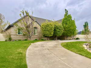 View of front of house with fence, curved driveway, a front lawn, and brick siding