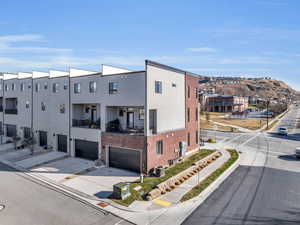 View of property with central air condition unit, an attached garage, and driveway