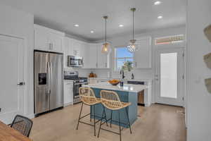 Kitchen with white cabinetry, appliances with stainless steel finishes, a breakfast bar area, and light countertops