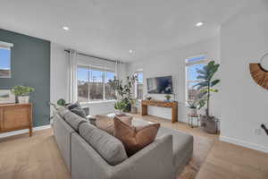 Living room with light wood finished floors, recessed lighting, and baseboards