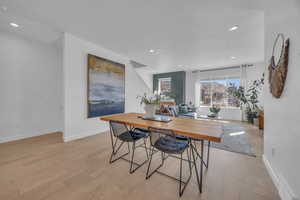 Dining room with light wood finished floors, visible vents, recessed lighting, and baseboards